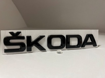 Логотип ŠKODA черного глянцевого цвета на багажнике.