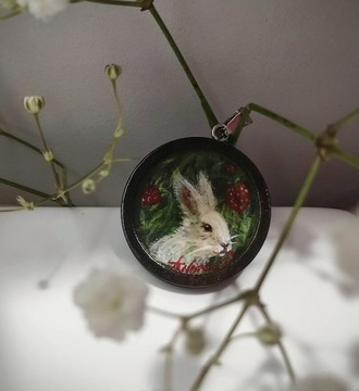 Wisiorek z obrazem białego króliczka i truskawek.