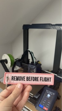 brelok haftowany "remove before flight" różowy