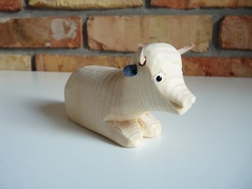 Drewniana rzeźbiona figurka leżącej krówki krowa
