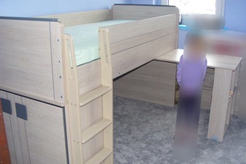 Łóżko z materacem, szafką i wysuwanym biurkiem.